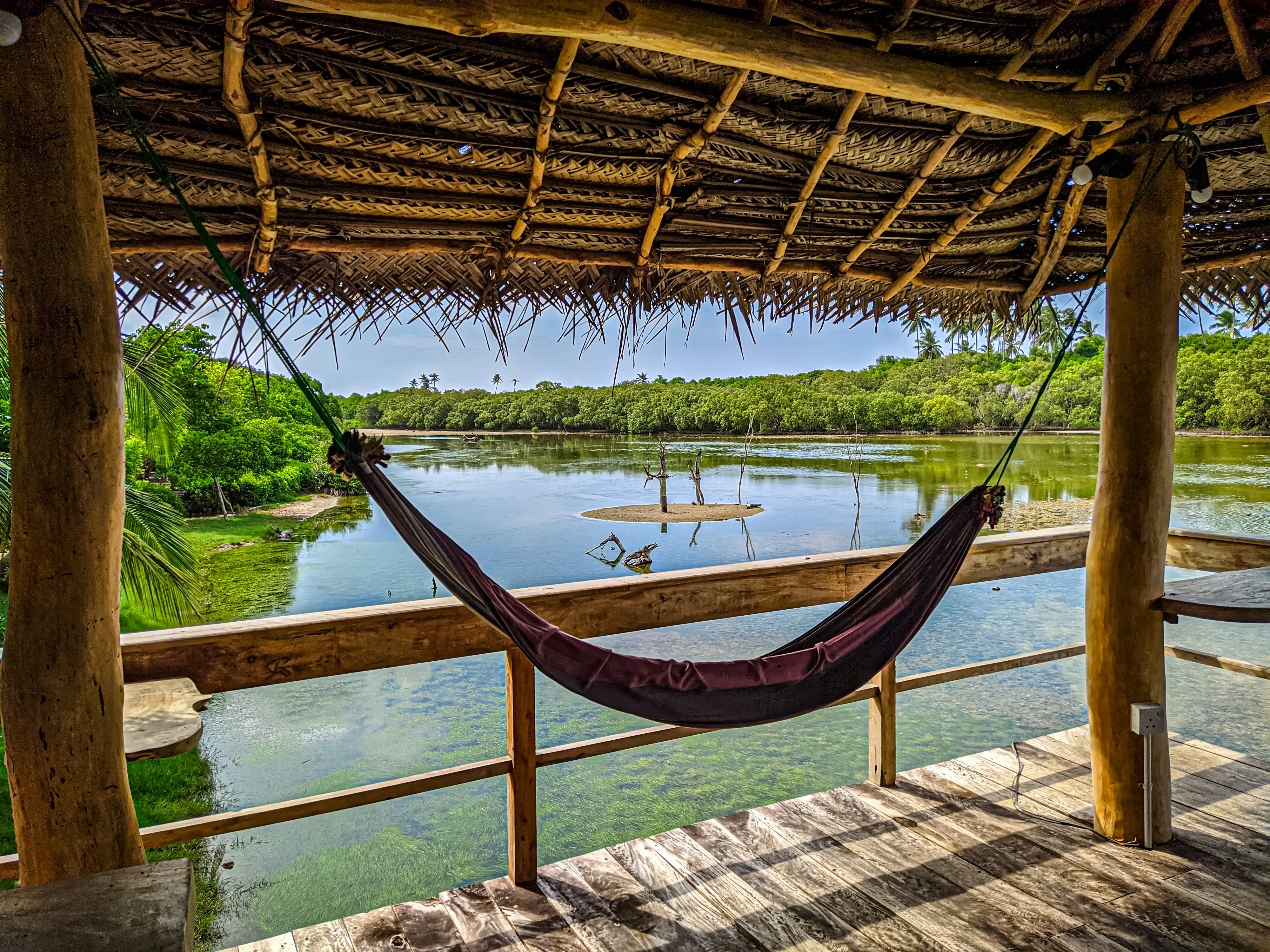 Hammock on a wooden deck facing water in a quiet lodge setting